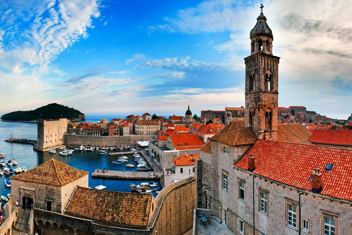People walking along Stradun in Dubrovnik’s Old Town beneath a sunset sky