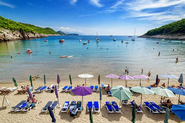 Beach with sun loungers, parasols and anchored boats in an Elafiti Islands bay